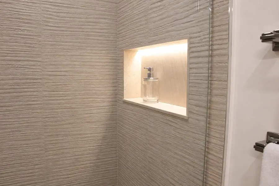 Lit shower niche set into textured wave tile