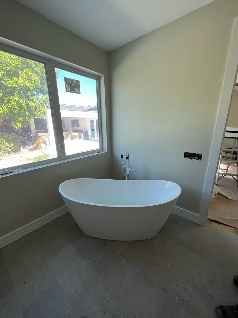 Freestanding tub beside a large window