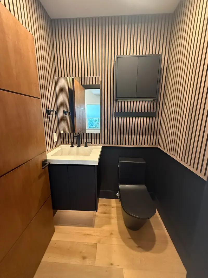 Powder room with wood slat walls, black wainscot and floating vanity